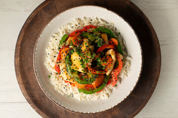 Chicken cooked in a wok with colorful peppers and rice.