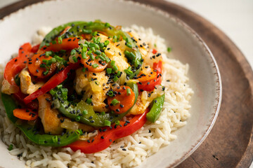 Chicken cooked in a wok with colorful peppers and rice.