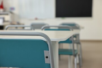 Empty school classroom with desks, blackboard and chairs