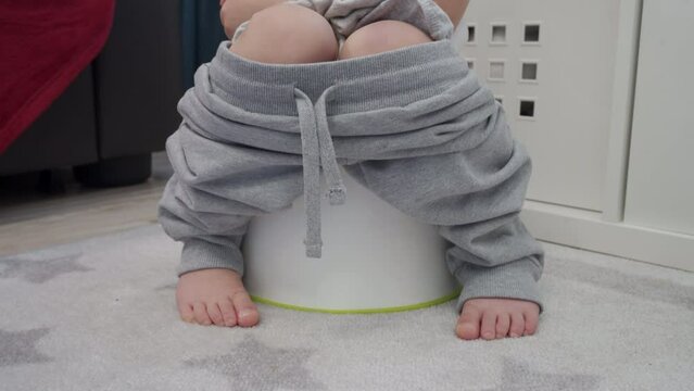 bare feet of child little boy sitting on a potty closeup
