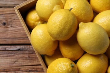 Fresh lemons in crate on wooden table, top view