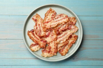 Delicious fried bacon slices on blue wooden table, top view