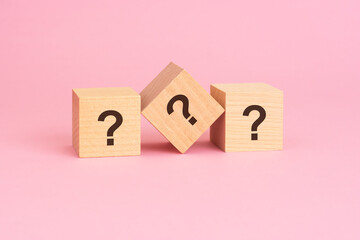 the questions sign on wooden cubes, pink background