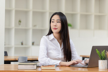 Happy asian young businesswoman using laptop at workplace.