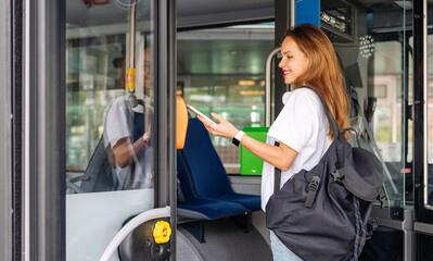 Beautiful urban woman paying bus by her smart phone.