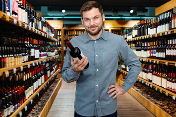 Man chooses a wine in a liquor store and smiling. Retail banner for winemakers and wine retailers.