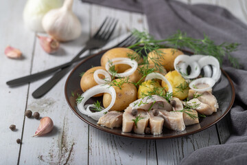 Traditional scandinavian food: salted herring slices with boiled potatoes and fresh raw onions..