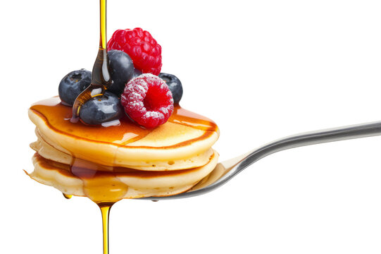 A fork with a stack of mini pancakes drizzled with syrup and topped with berries creates a delicious breakfast close-up.