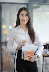 Happy asian young businesswoman holding documents folders in office working space, Asian female...