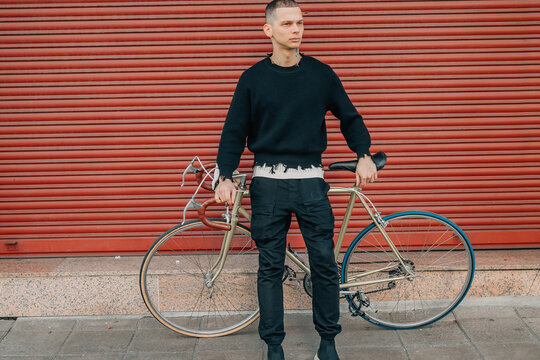 young man with bicycle on the street in red background