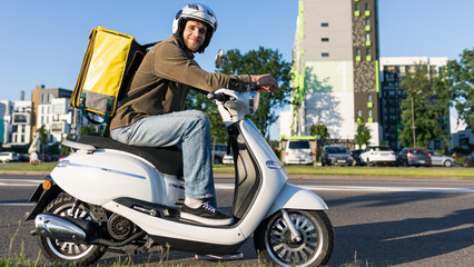A delivery man on a scooter stands on the road while delivering groceries to a customer. Courier with a yellow bag