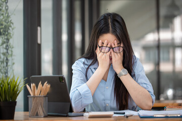 Obraz premium Asian businesswoman are stressed and tired from work sitting at desk in the office, feeling sick at work, stress from work.