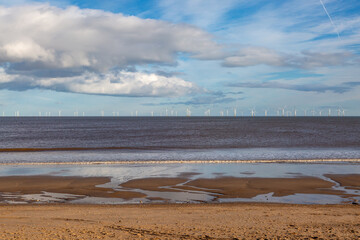 The sandy beach and ocean at Skegness, with an off shore wind farm on the horizon