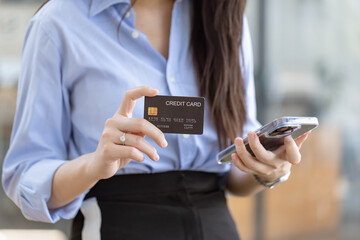 Young asian businesswoman using a credit card with smartphone at at office, Happy shopping online and credit card concept.