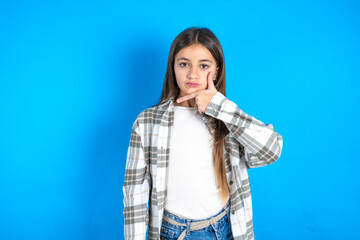 Young beautiful teen girl wearing check shirt looking confident at the camera smiling with crossed arms and hand raised on chin. Thinking positive.