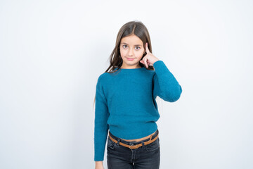 Young beautiful teen girl wearing blue T-shirt tries to memorize something, keeps fore finger on temple, reminds information for exam,