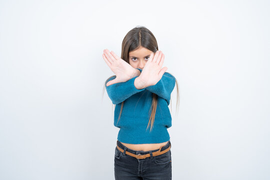 Young beautiful teen girl wearing blue T-shirt has rejection expression crossing arms and palms doing negative sign, angry face.