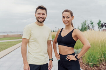 Fit couple posing after a workout session in a park with city views, sharing a healthy routine.