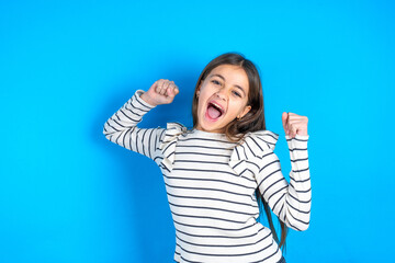 Ecstatic Young beautiful teen girl wearing striped T-shirt shout loud yeah fist up raise win lottery