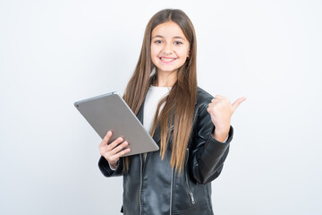 Naklejka premium Young beautiful teen girl wearing biker jacket pointing empty space modern device
