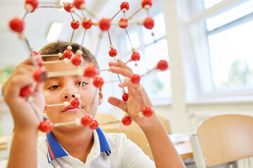 Boy holding molecular structure in elementary school