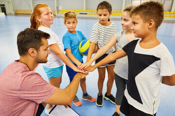 Students stacking hands with teacher in gym class