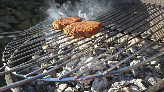Meat patties on the grill in the sunshine