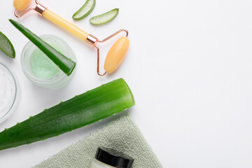 Flat lay composition with cosmetic products and cut aloe leaves on white background. Space for text