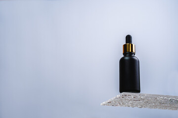 Facial serum in a dark bottle. Bottle with essence with water drops. Moisturizing and whitening serum. Essence for facial skin