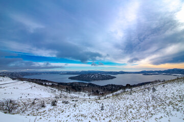 雪に覆われた峠の斜面から見下ろす湖。日本の北海道の観光名所の美幌峠での屈斜路湖の眺め。