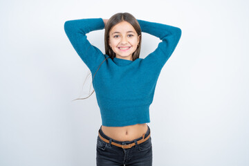 Satisfied beautiful kid girl wearing blue sweater hold hands behind head relaxing