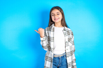 Lovely Beautiful kid girl wearing plaid shirt pointing aside with forefinger, showing at copy space having news about bargains