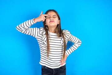 Beautiful kid girl wearing striped T-shirt pointing unhappy at pimple on forehead, blackhead  infection. Skincare concept.