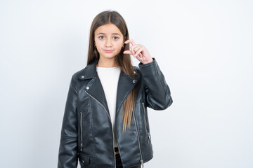 beautiful kid girl wearing biker jacket purses lip and gestures with hand, shows something very little.