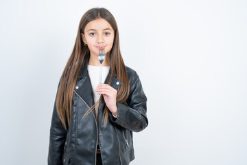 Photo of dreamy beautiful kid girl wearing biker jacket over white background lick fork look empty space