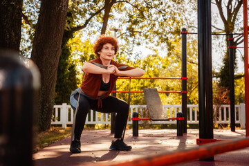 Mid adult Caucasian woman wearing sportswear squatting with sports elastic band. Autumn sports...
