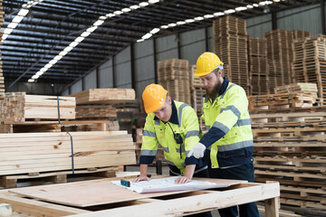 Warehouse and factory concept. Group of male warehouse workers working and discussing structure blueprint building in lumber storage warehouse