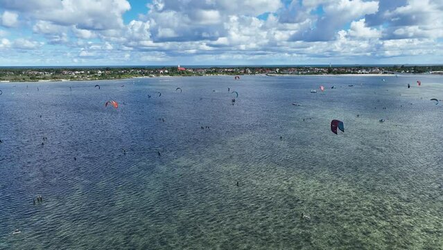 People swim in the sea on a kiteboard or kitesurfing. Summer sport learning how to kitesurf. Kite surfing on Puck bay in Jastarnia, Poland, Europe aerial drone photo view