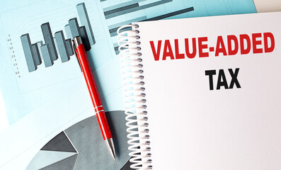 VALUE-ADDED TAX text on a notebook with pen on a chart background - Powered by Adobe