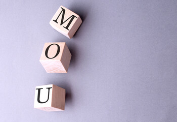 Word MOU on wooden block on the grey background