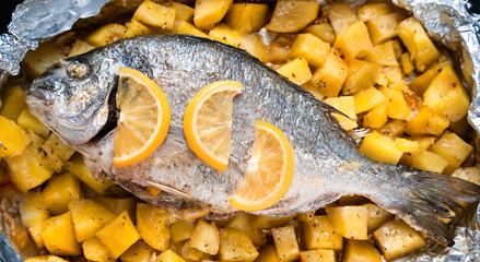 Baked fish Dorado with potatoes in the oven. Top view. Close-up. Selective focus.