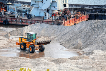 Bulldozer with sand in a scoop, barge on background - 734899144