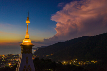 aerial view scenery sunset above pagoda of Doi Thepnimit temple on the highest of Patong mountain..The lights twinkle at twilight background..Scene of Colorful romantic sky sunset, beautiful pagoda.