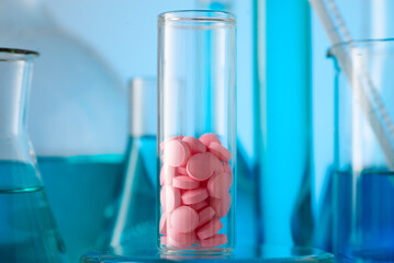 Pink tablets in a chemical test tube. Production of medicines Medicine, pharmaceuticals, chemistry