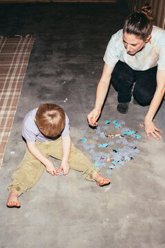 High angle view of boy solving puzzle with mother while sitting on floor at home