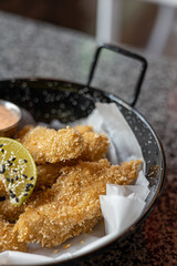 golden deep-fried battered chicken nuggets.succulent chicken chunks ensconced in a delectable batter, crisped up with Panko, and draped in sauce closeup on the plate on the table.