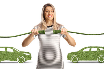 Young woman holding green cables in front of electric cars