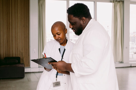 Male and female medical workers discussing over clipboard at hospital