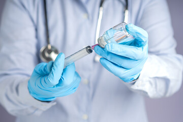 Doctor holding a syringe and vial with medication for injection.