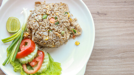 Pork fried rice served in a restaurant with wooden floor tables with tomatoes, cucumbers, scallions, fried rice, delicious food made from steamed rice, top view